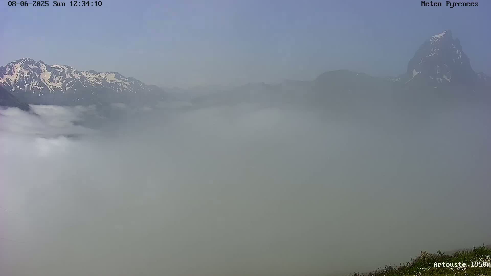 A hazy, foggy landscape shows snow-capped mountains in the distance, partially obscured by a thick layer of fog.