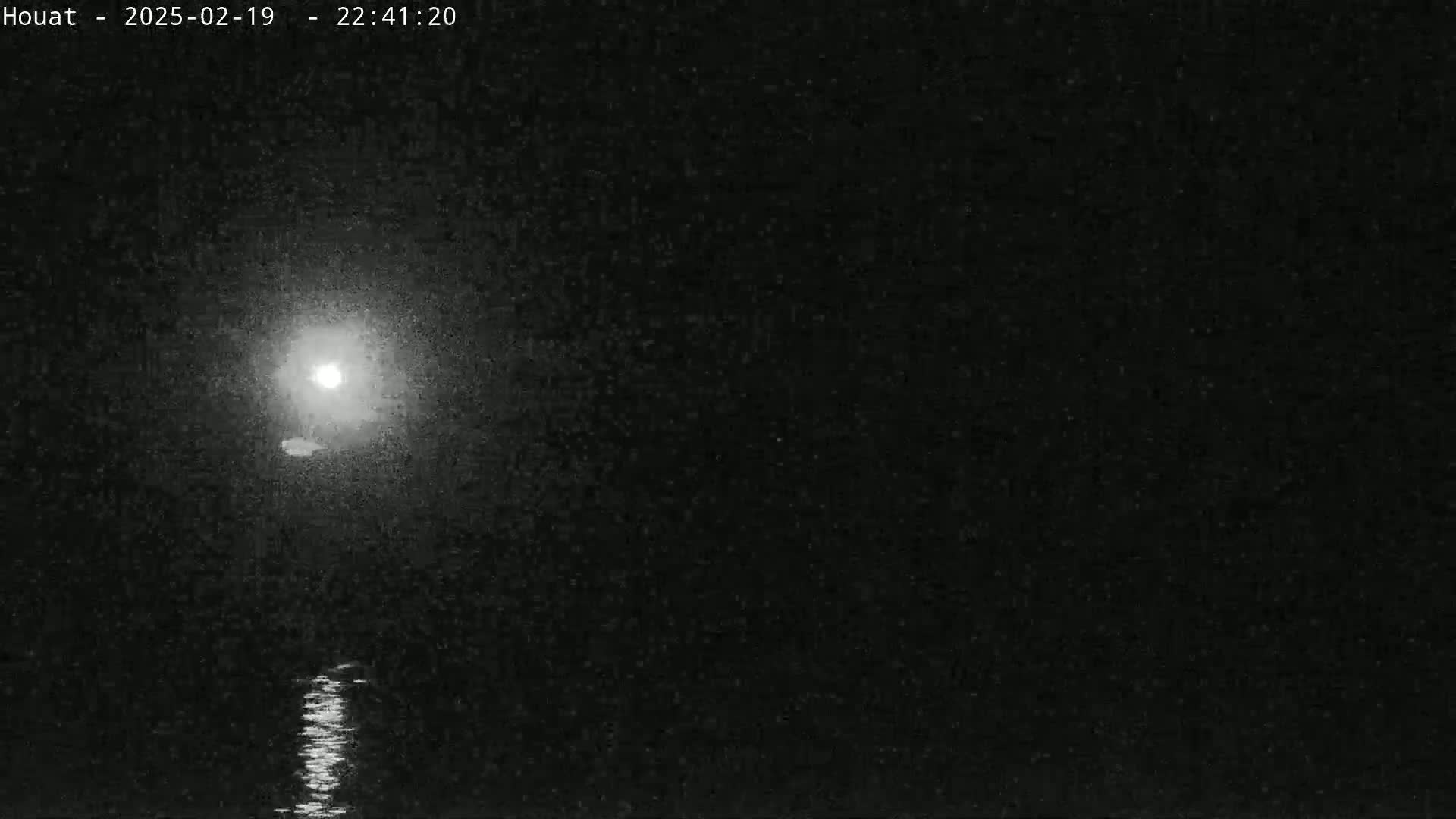 A bright moon shines over dark, calm water at night.
