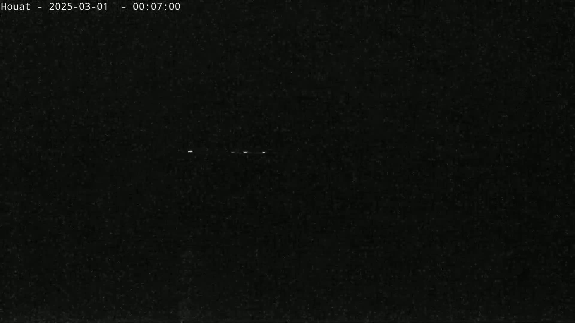 A nighttime, dark image shows several faint white lights in the distance.