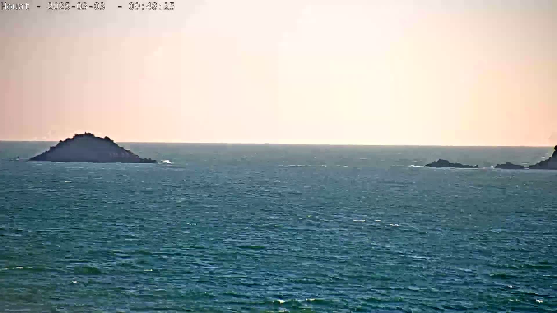 Two small islands are visible on a calm sea under a pale, mostly clear sky.