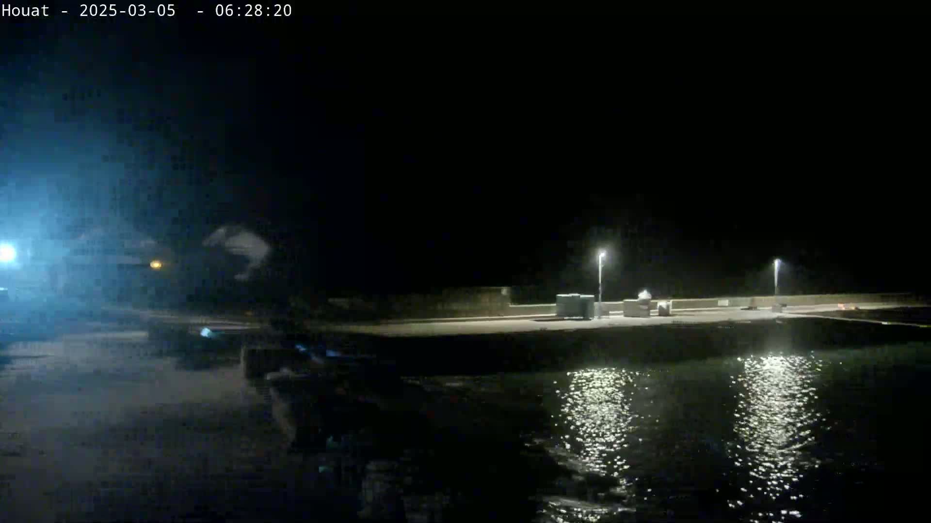 A nighttime view of a calm body of water reflecting lights from a low-lit waterfront area.