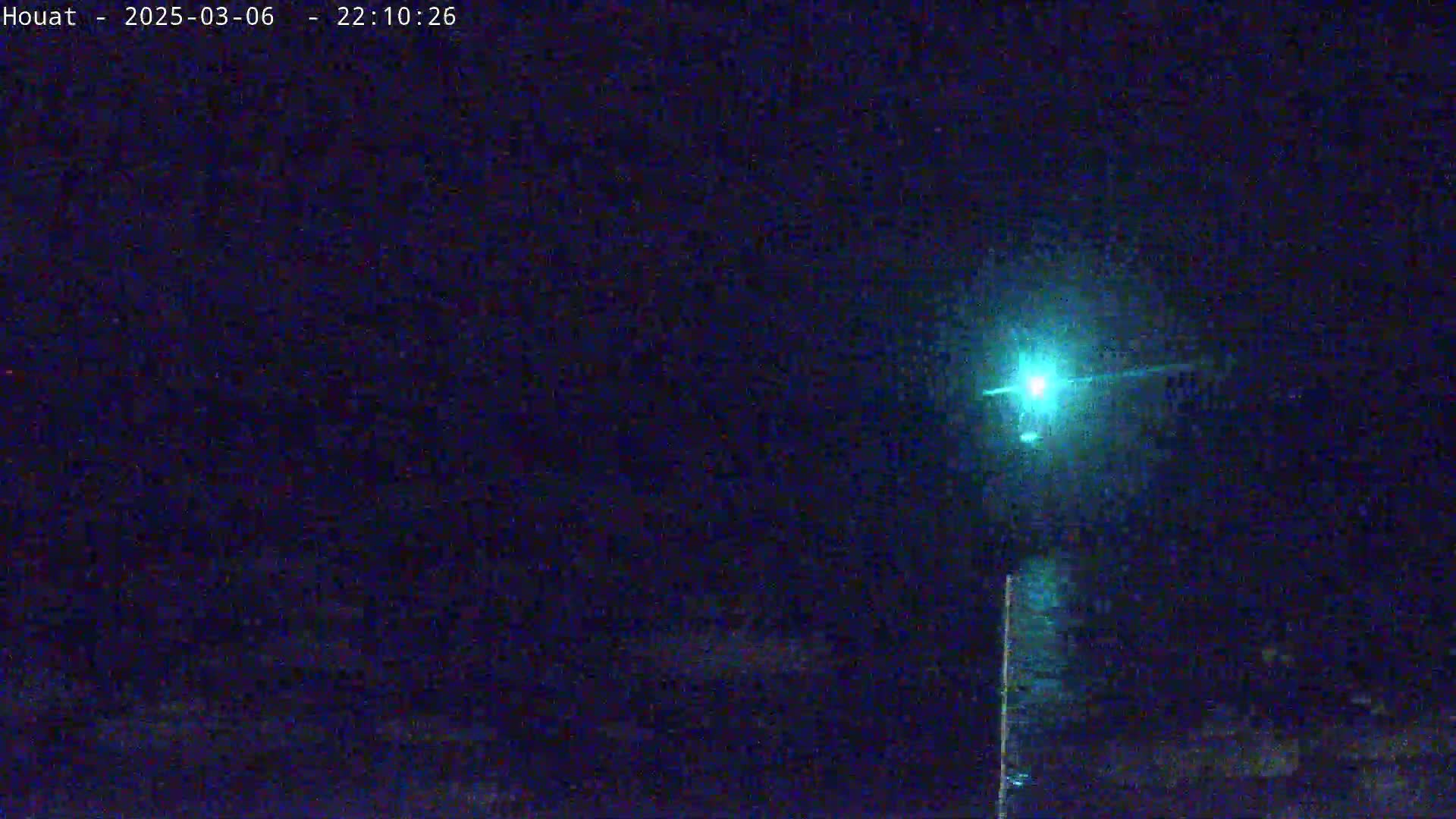 A bright teal light shines in the night sky.
