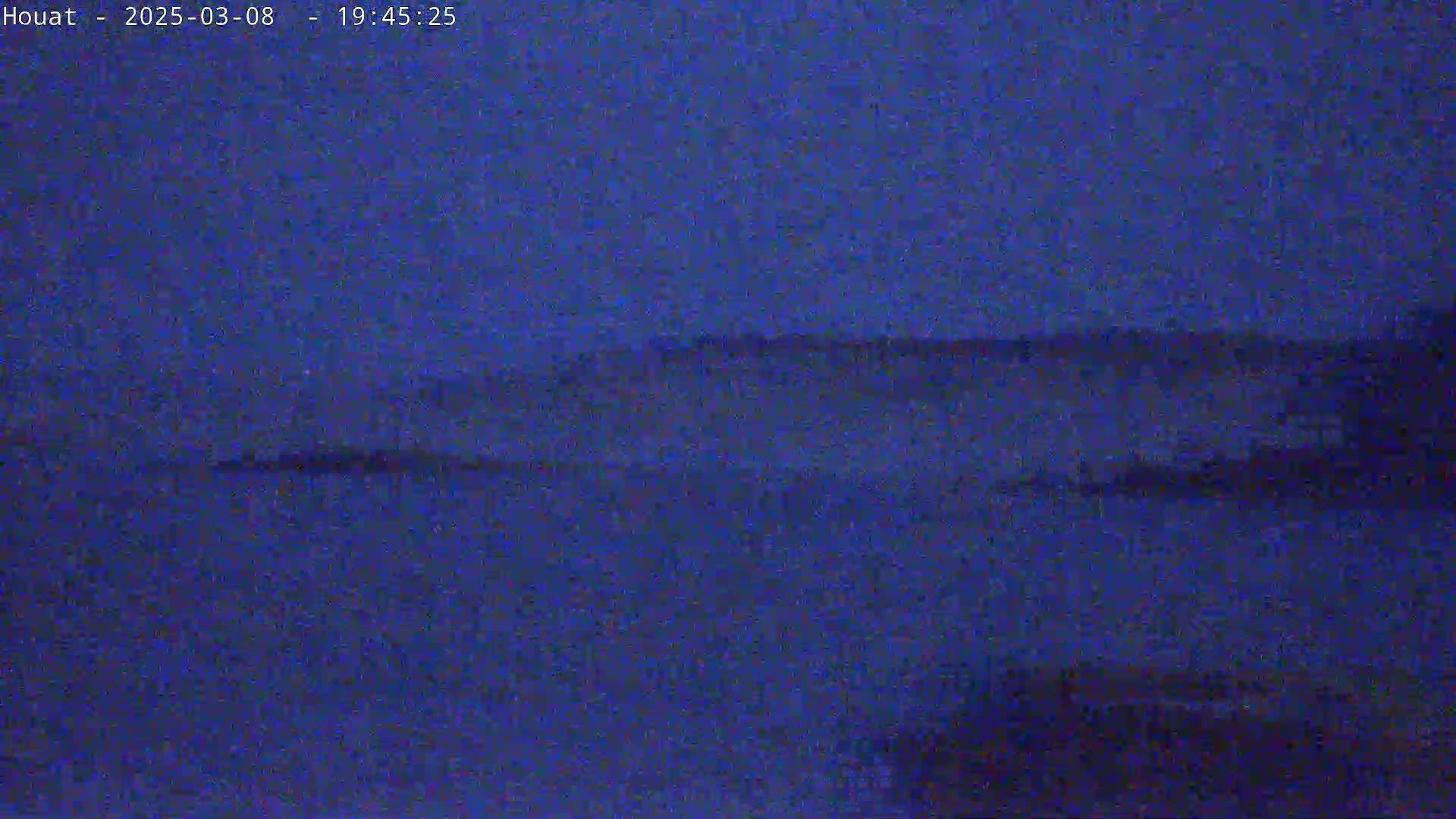 A dark, blurry image shows a dark body of water under a night sky.
