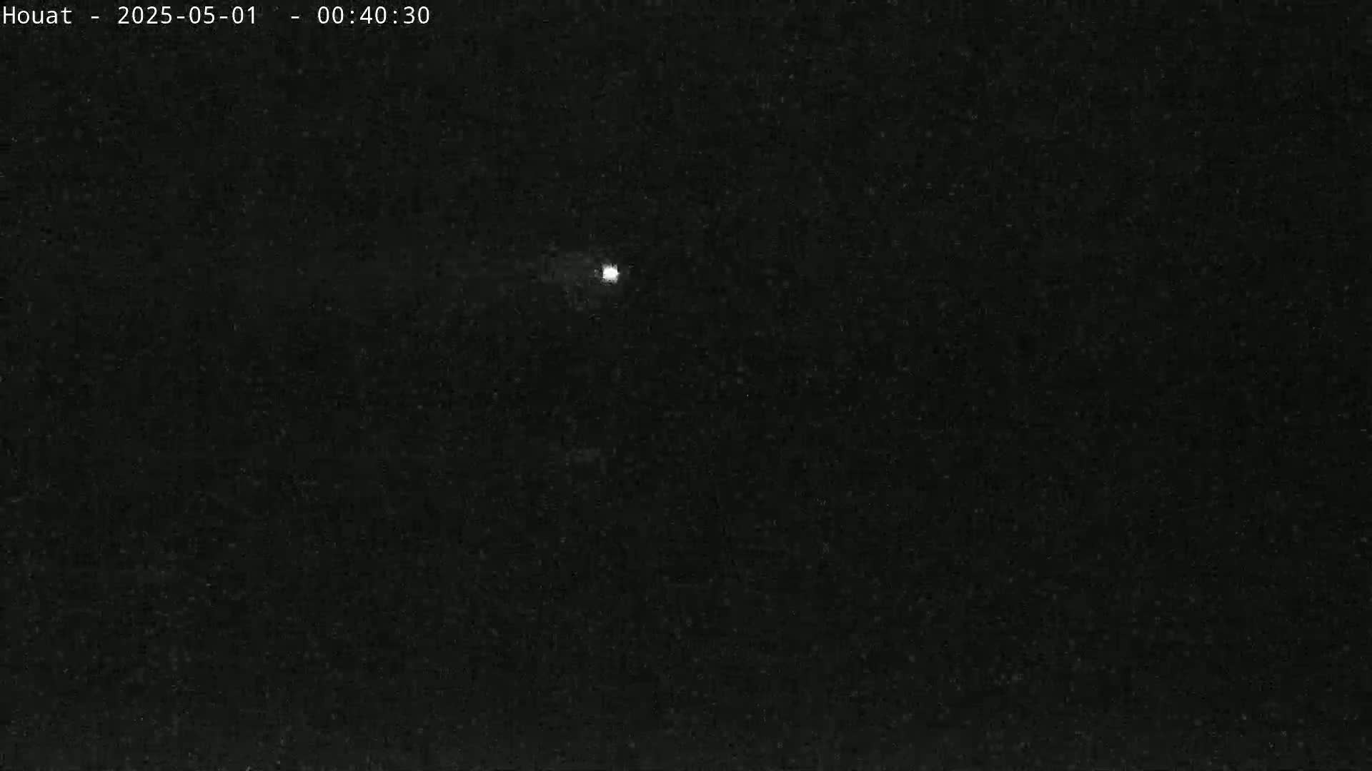 A single, small, bright light is visible in the center of a dark, nighttime sky.