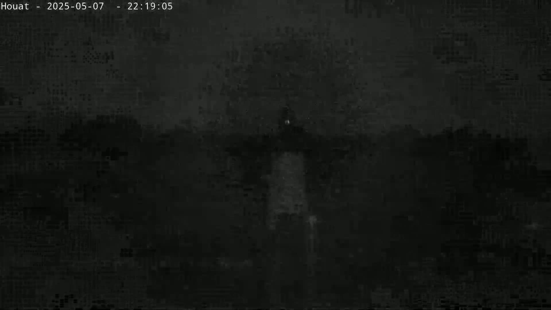 A low-light nighttime image shows a dark, indistinct landscape.