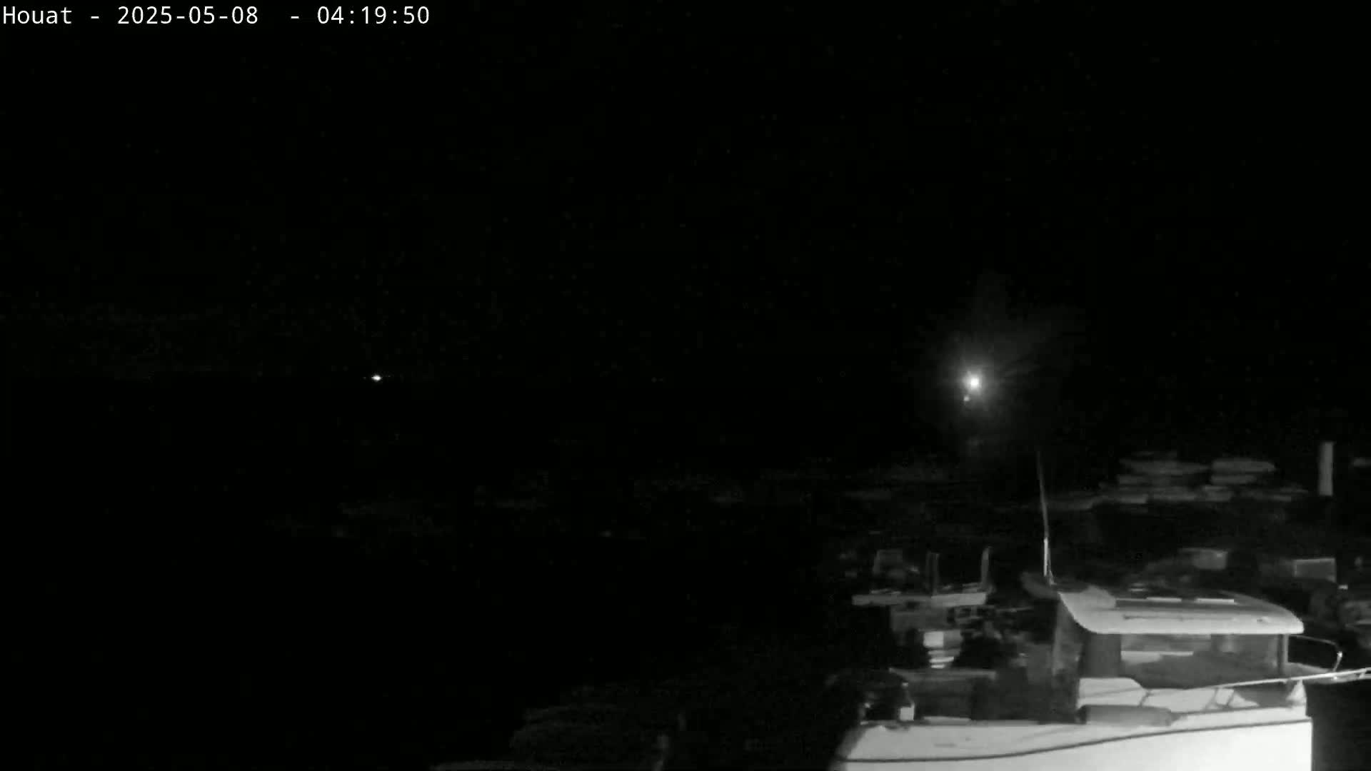 A nighttime, low-light view of a boat at a dock under a dark sky with a few distant lights visible.