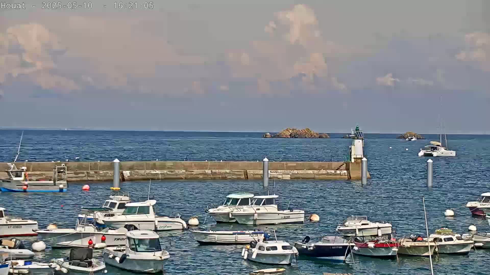 A harbor filled with numerous motorboats and sailboats under a partly cloudy sky.