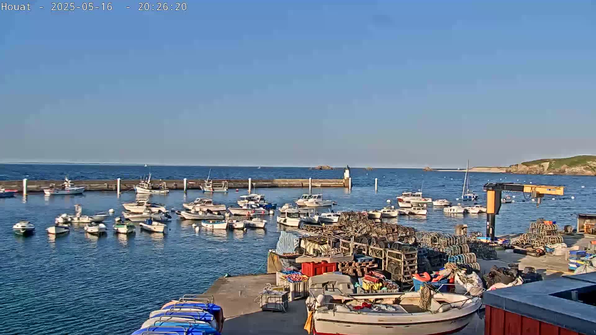 A harbor filled with numerous small boats and fishing equipment under a clear blue sky.