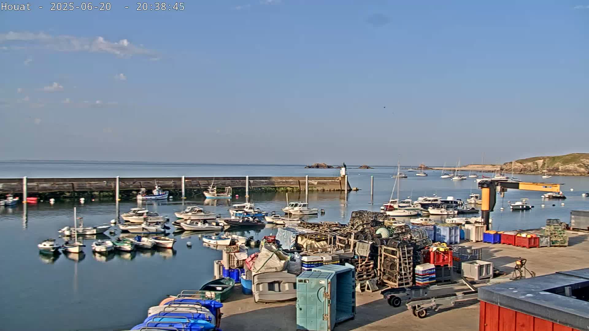 A harbor filled with numerous small boats under a mostly clear blue sky with a few scattered clouds.