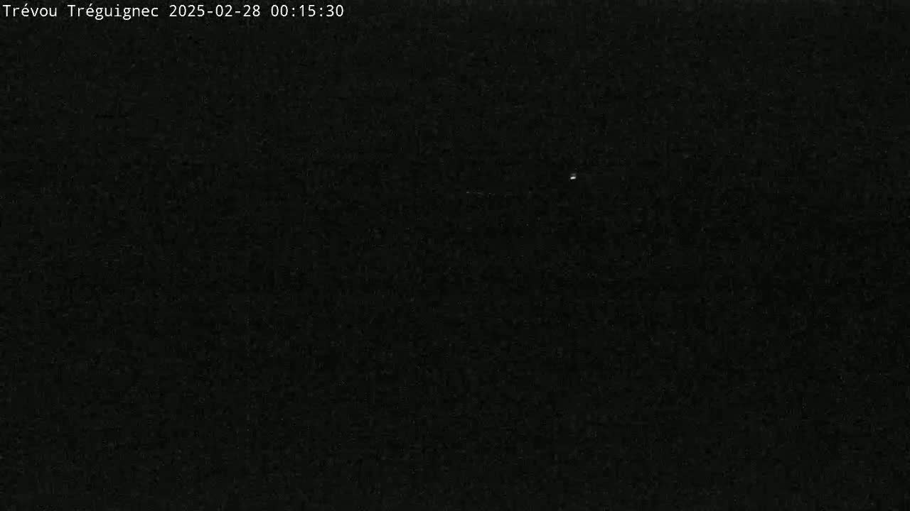 The image shows a dark, nighttime scene with a few barely visible lights in the distance.