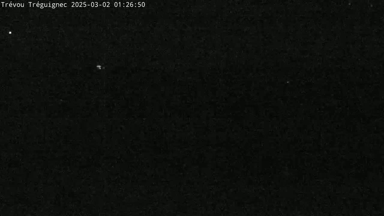 A dark, nighttime scene shows a mostly black sky with a few faint, bright spots.