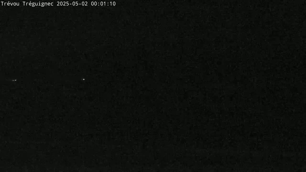 A dark, nighttime scene shows two faint lights in the distance under a clear, black sky.