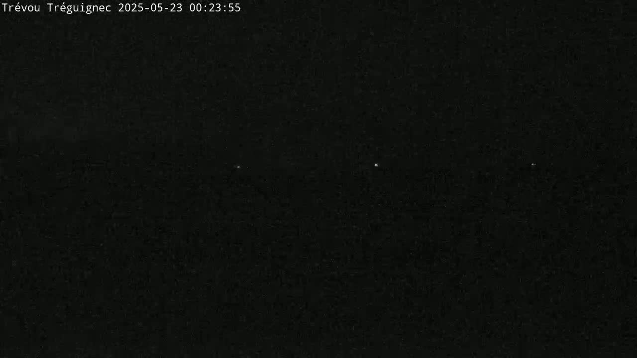A nighttime image shows a dark, mostly featureless scene with three faint lights visible in the distance.