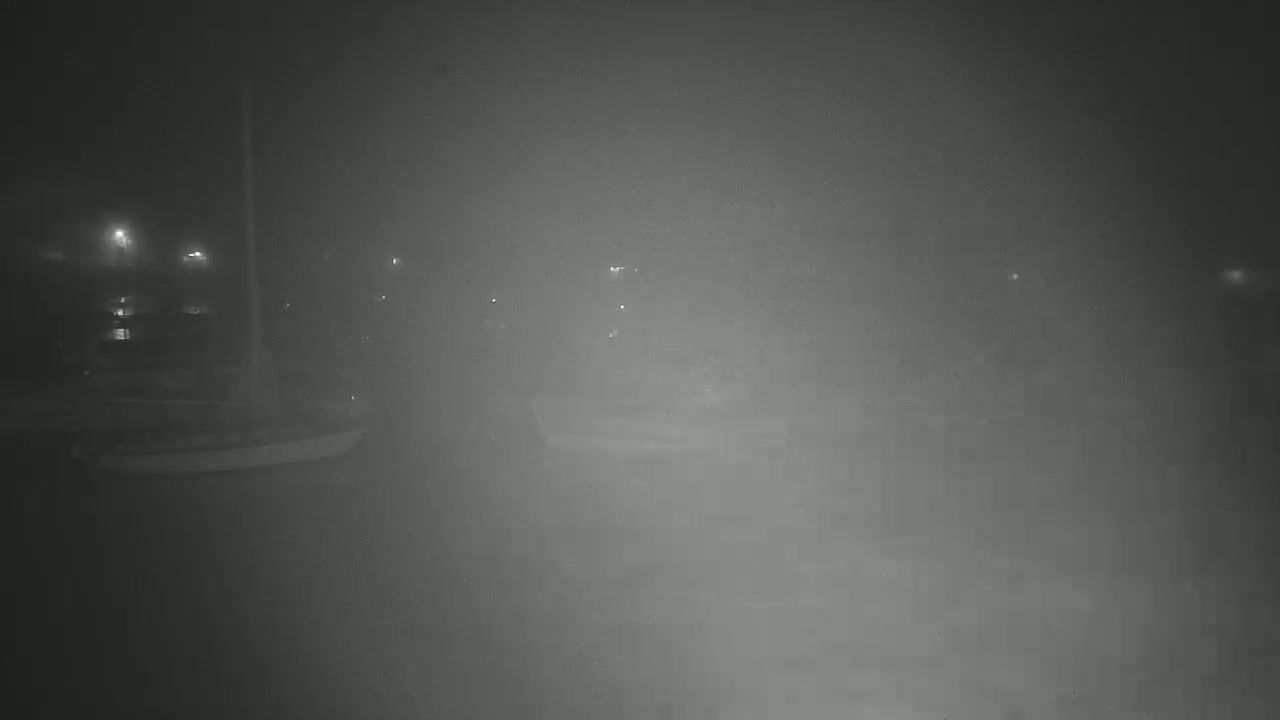 A foggy night scene shows a small boat and indistinct shapes in the distance, illuminated by faint lights.