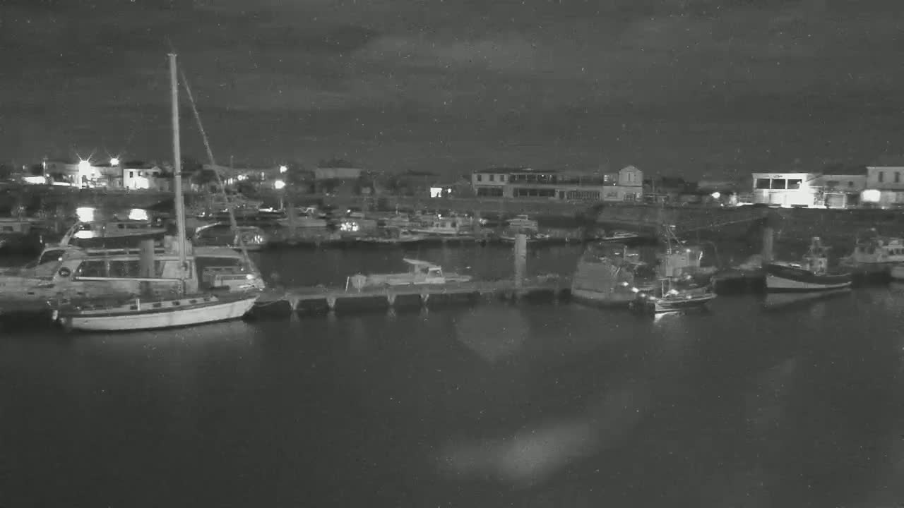A nighttime view of a harbor filled with docked boats under a dark, cloudy sky.