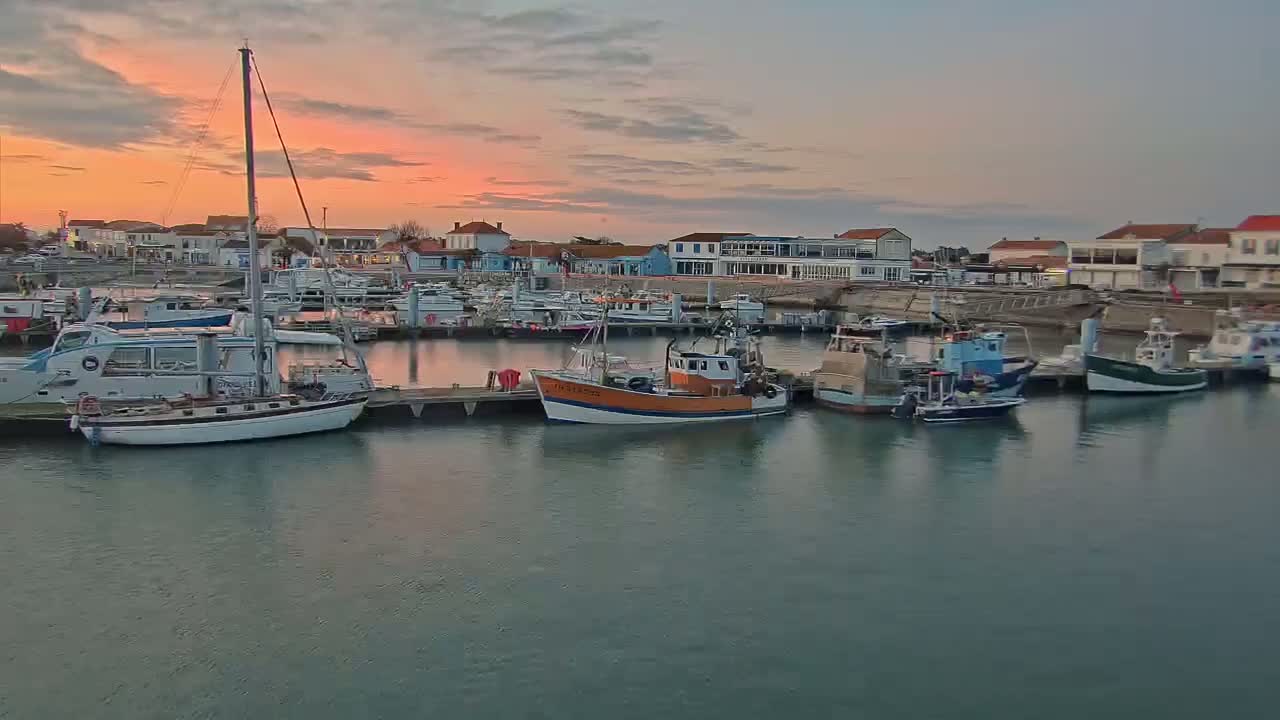 A harbor filled with various boats at sunset under a mostly clear sky.