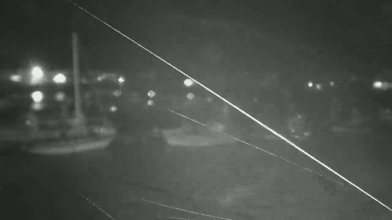 A blurry, nighttime view of out-of-focus lights and indistinct shapes, possibly vehicles or people, seen through a scratched surface.