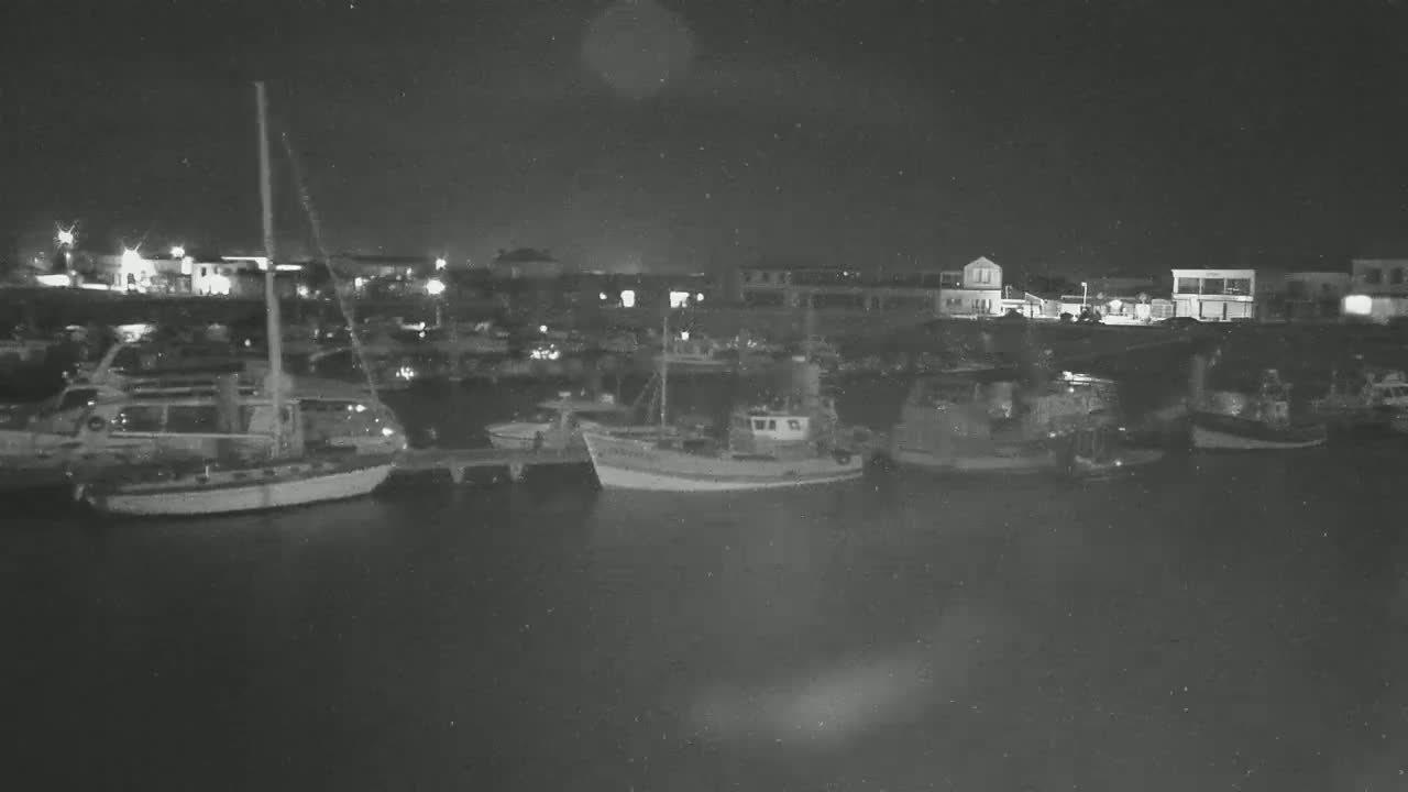 Several boats are moored at a harbor at night under a dark sky.