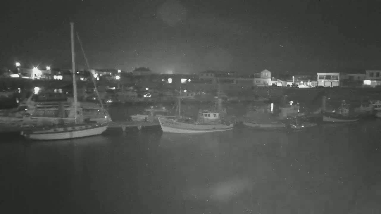 Several boats are moored in a harbor at night under a dark, clear sky.