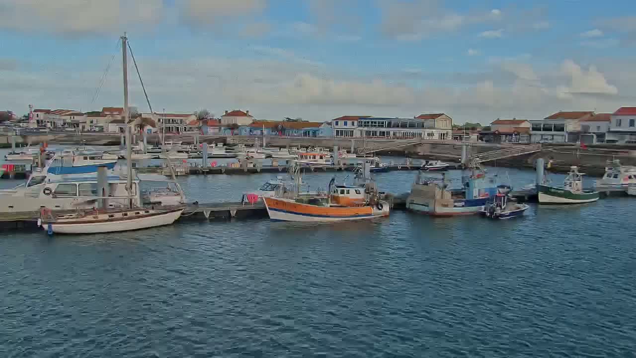 A harbor filled with various sized boats under a partly cloudy sky.