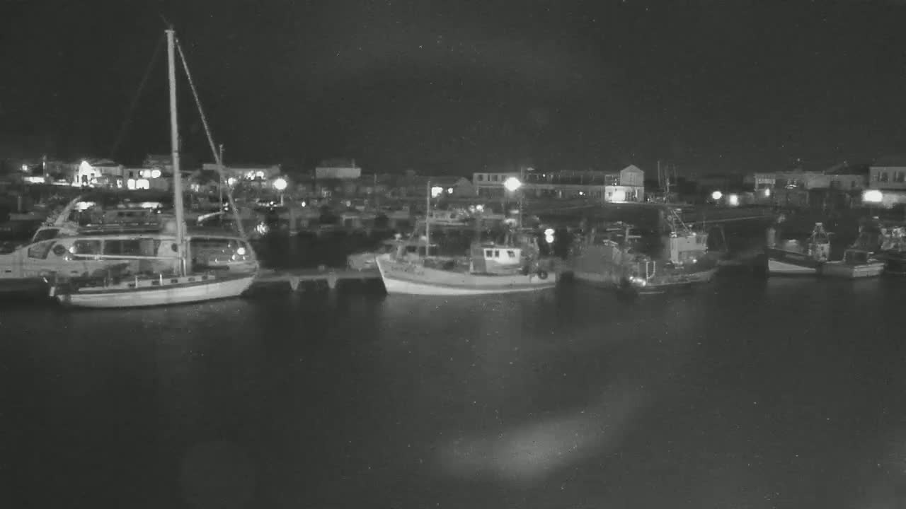 Several boats are moored at a harbor at night under a dark sky.