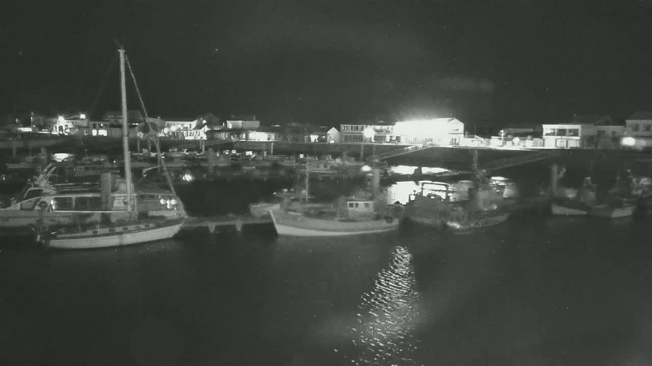 Several boats are moored at a harbor at night under a dark sky.