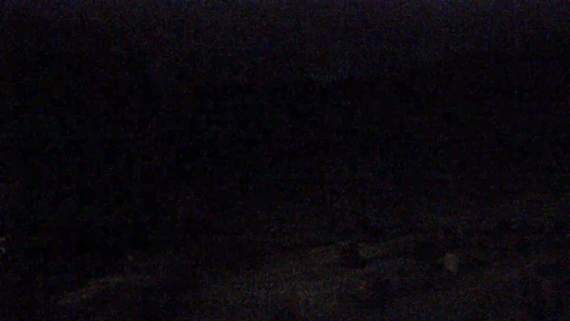 The image shows a dark, nighttime scene with indistinct shapes in the distance.