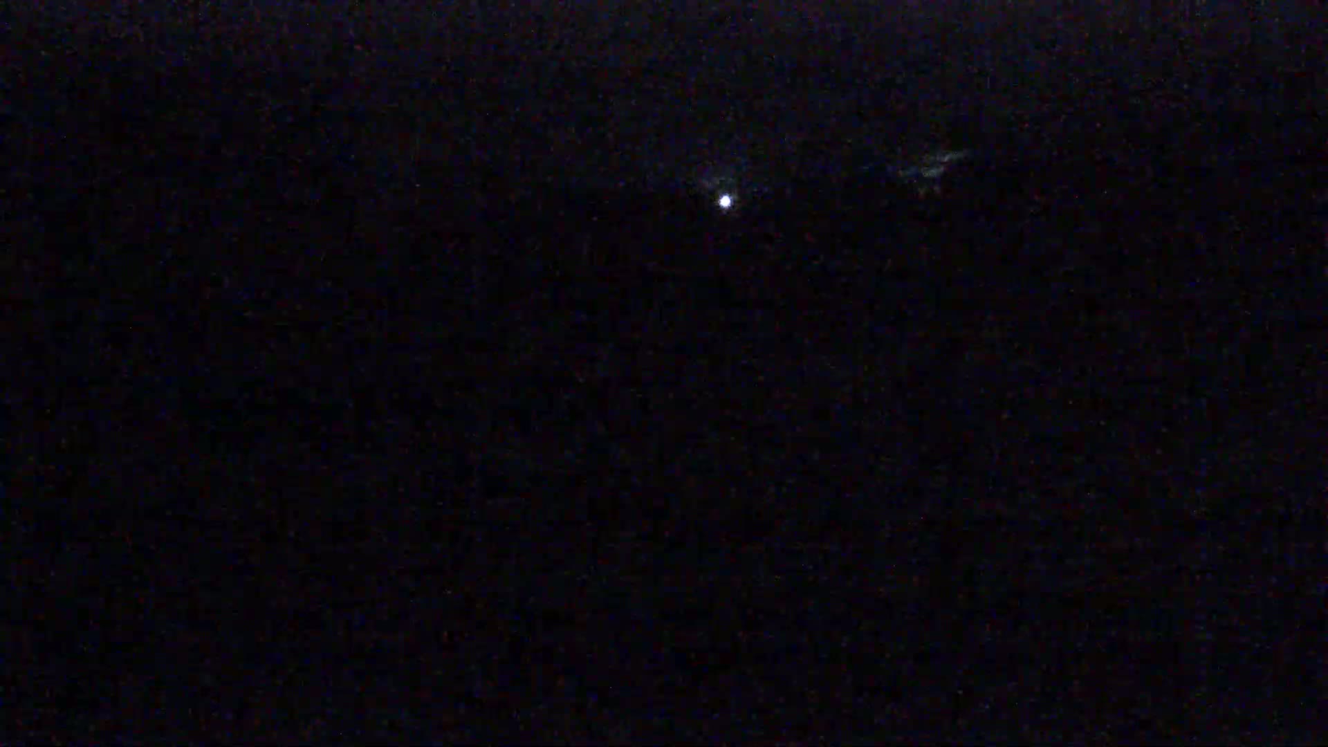 A single, bright light is visible in the dark night sky.