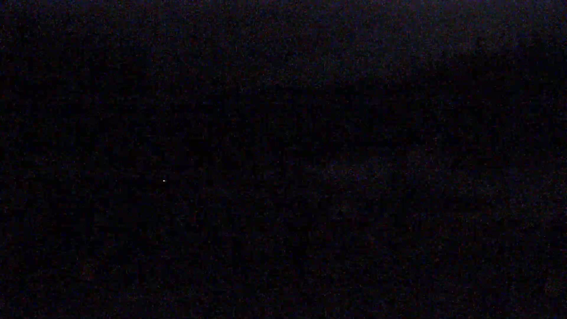 A dark, possibly nighttime scene with a few faint specks of light visible.