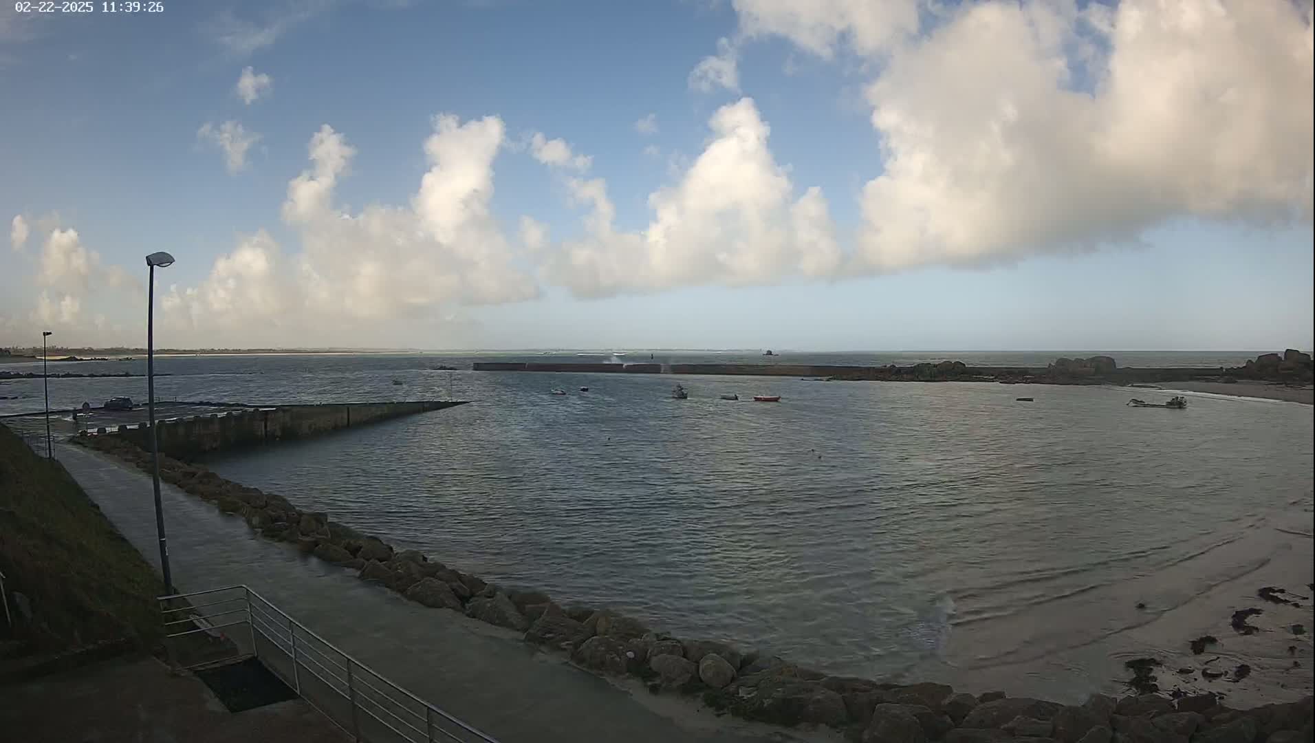 A calm harbor with a few small boats under a partly cloudy sky.