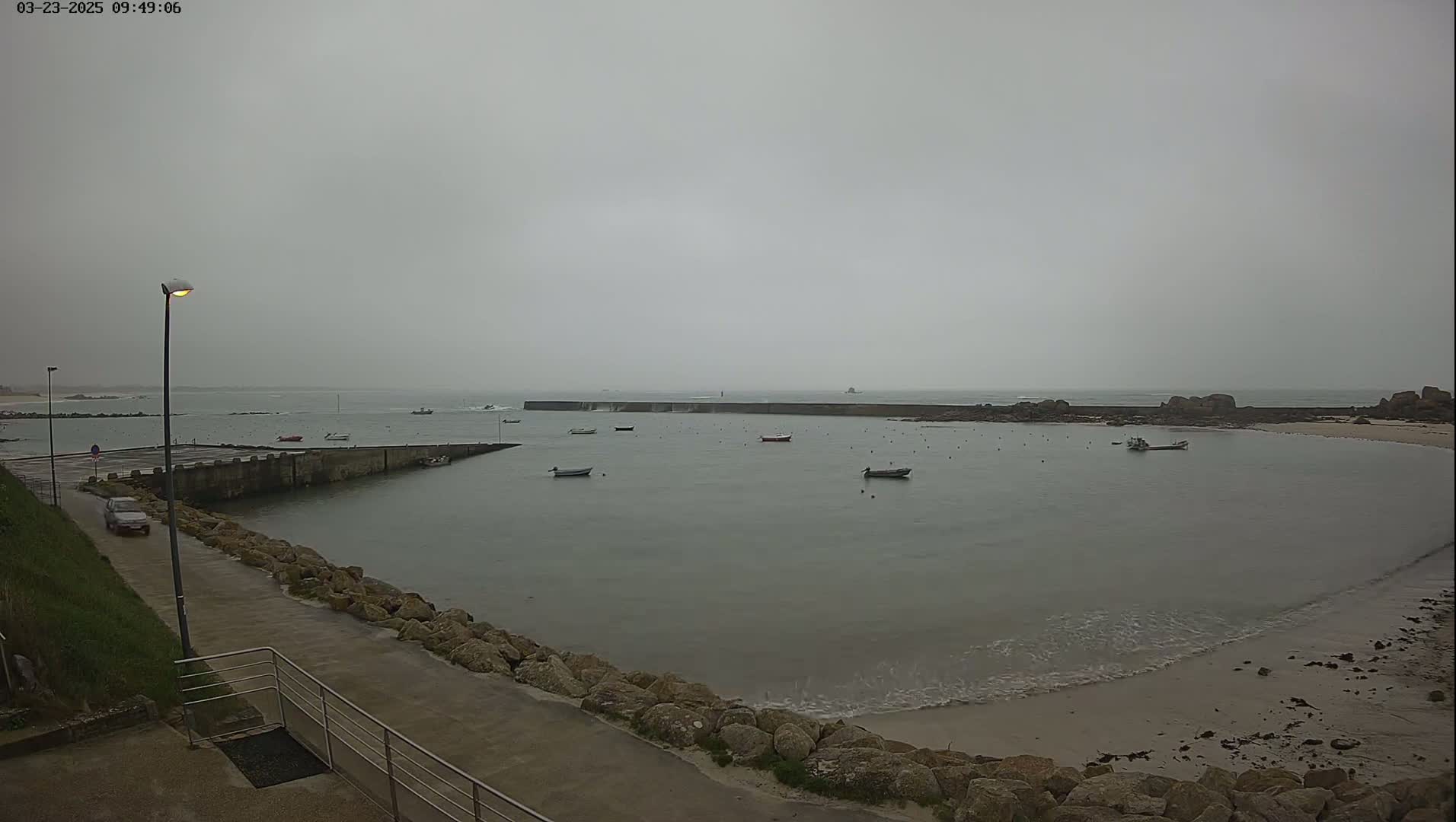 A calm bay with several small boats is seen from a high vantage point on an overcast day.