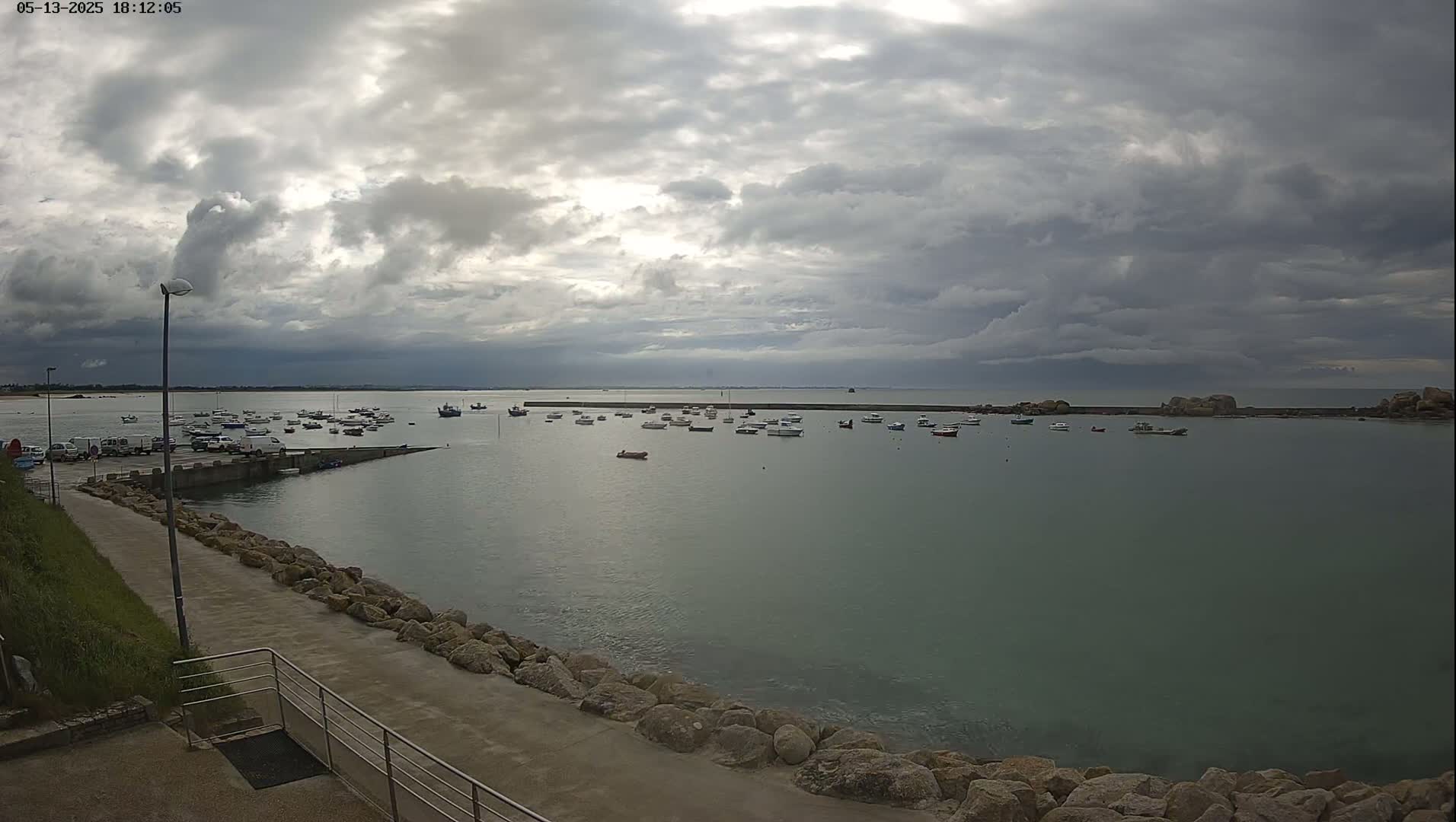 Numerous small boats are moored in a calm harbor under a cloudy sky.