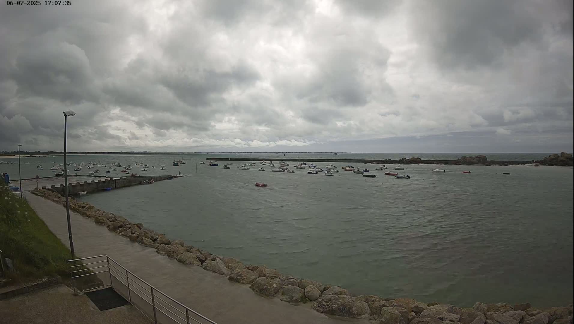 A harbor filled with numerous small boats is seen under an overcast sky.