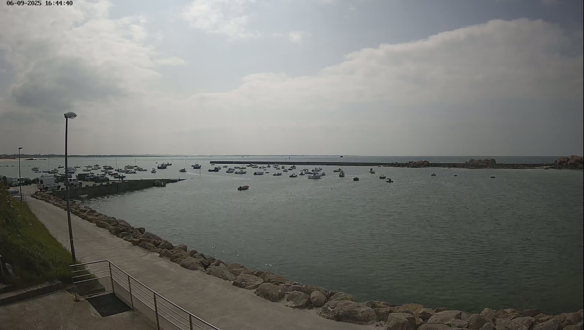 A harbor filled with numerous small boats is seen under a partly cloudy sky.