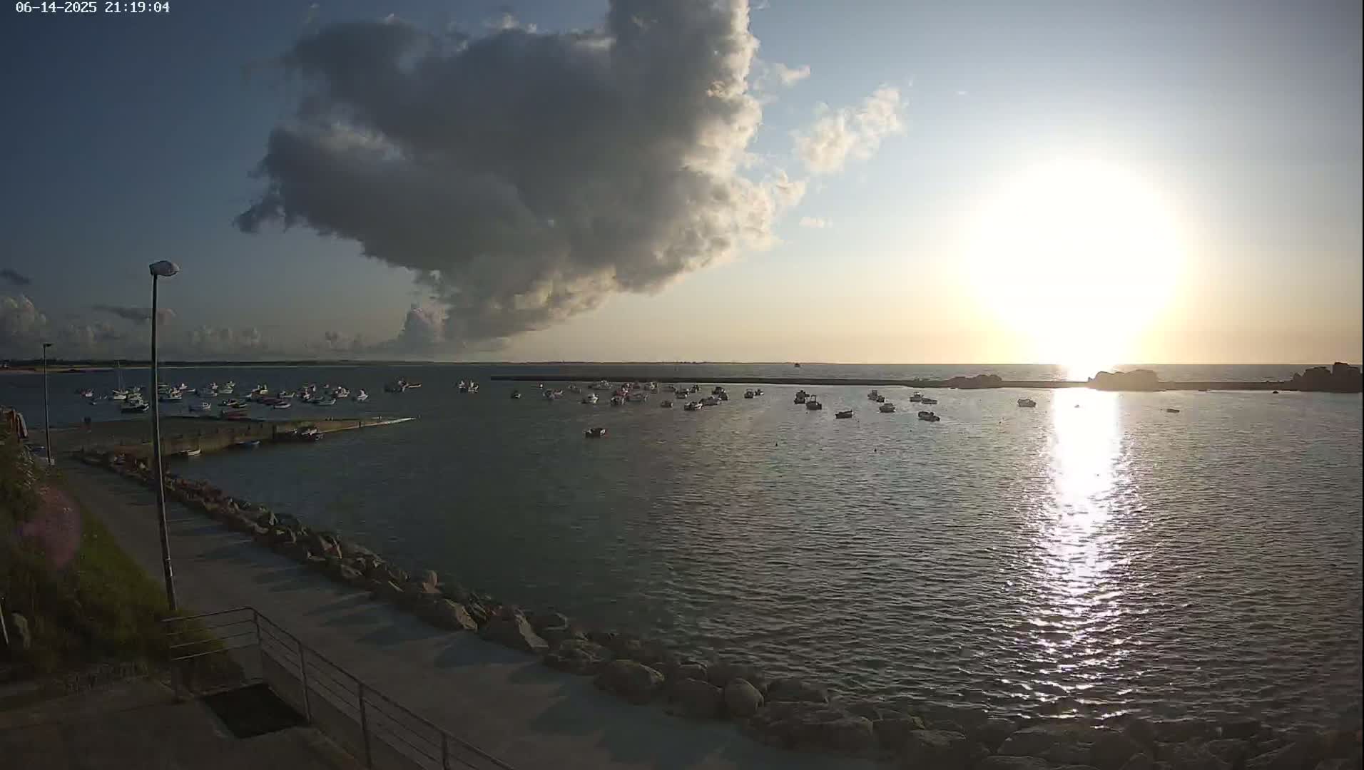 A harbor filled with small boats under a partly cloudy sky.