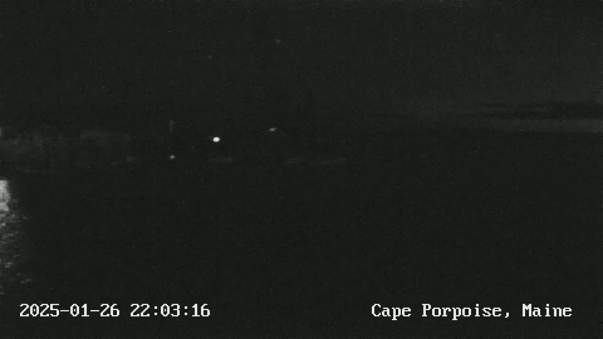 The image shows a dark, nighttime scene of a body of water under a clear sky.
