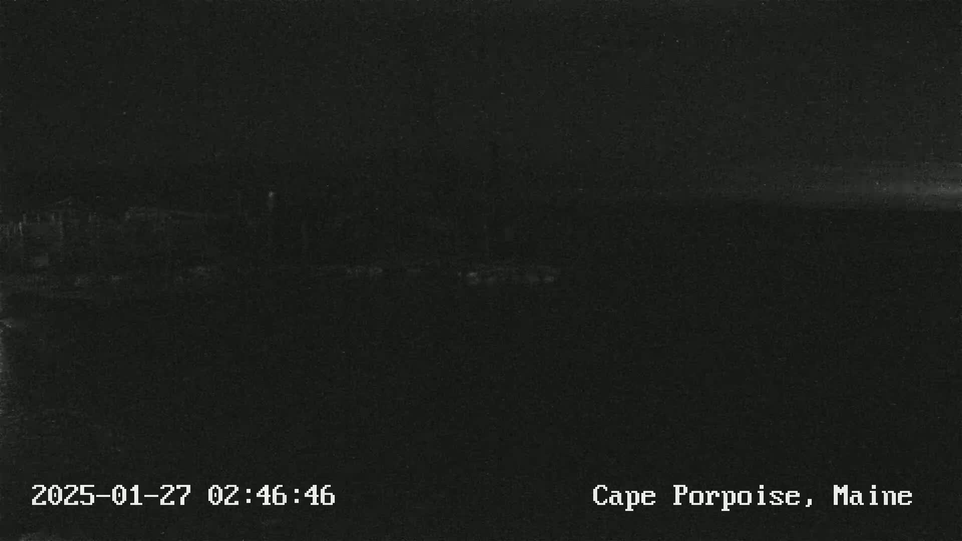 A dark, nighttime image shows a barely visible horizon line under a mostly clear sky.