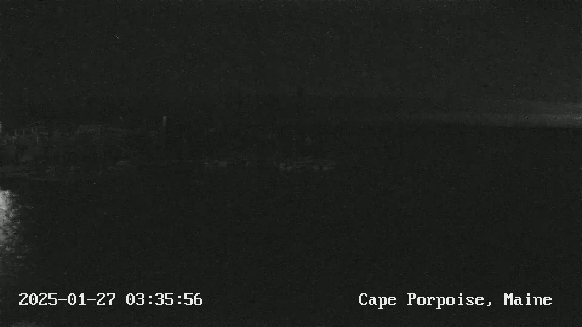 A dark, nighttime image shows a low-light view of a landmass, possibly near the coast.