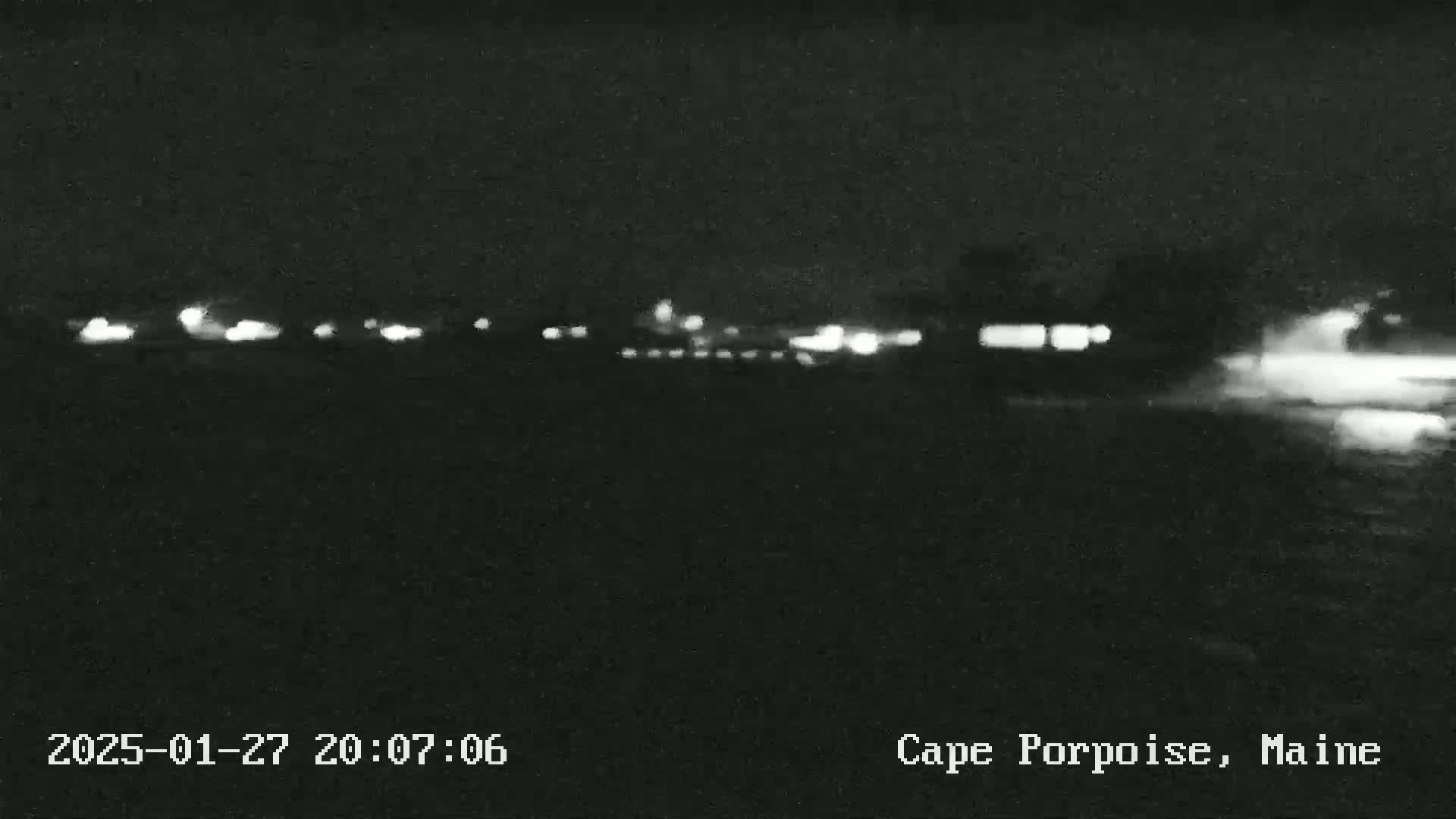 A nighttime, low-light view of a dark landscape with distant lights.