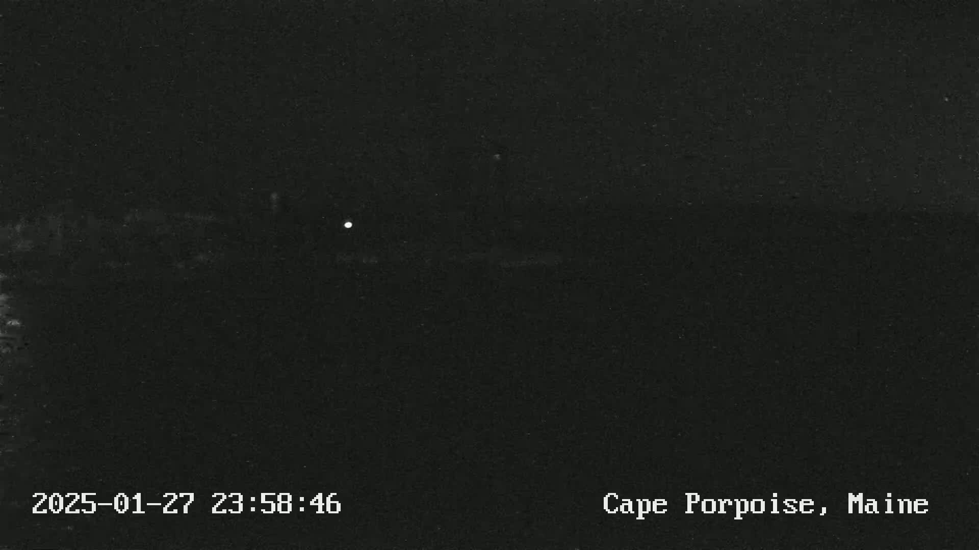 A nighttime, dark image shows a single, small, bright light in the distance.
