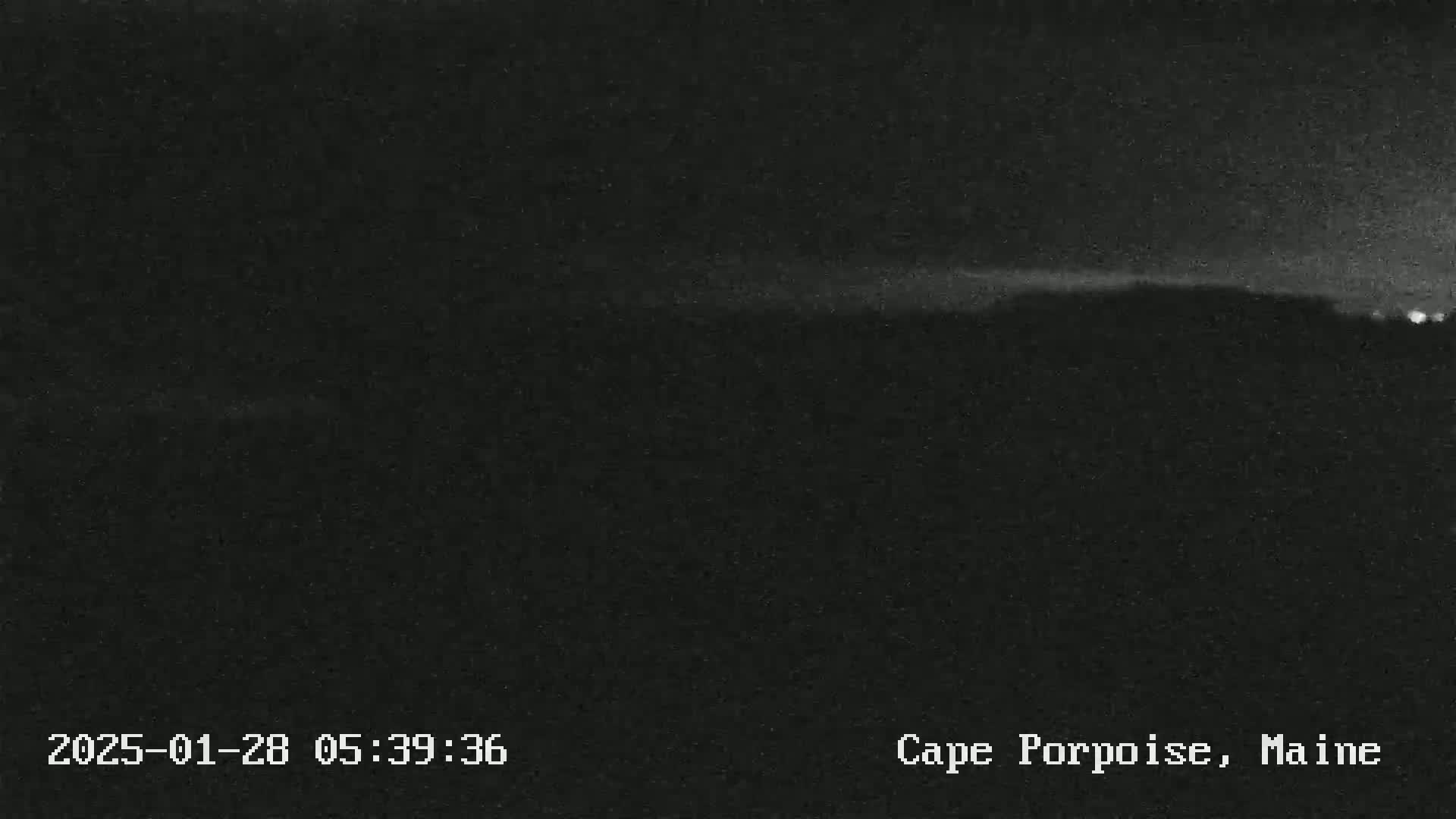 A dark, nighttime landscape shows a faint horizon line under a mostly clear sky.