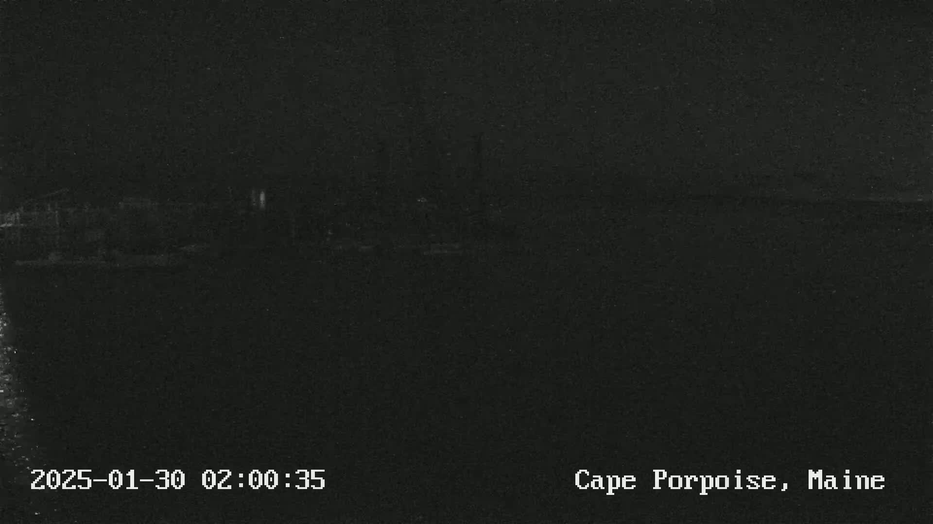 A dark, nighttime image shows a blurry, indistinct shoreline under a seemingly clear sky.