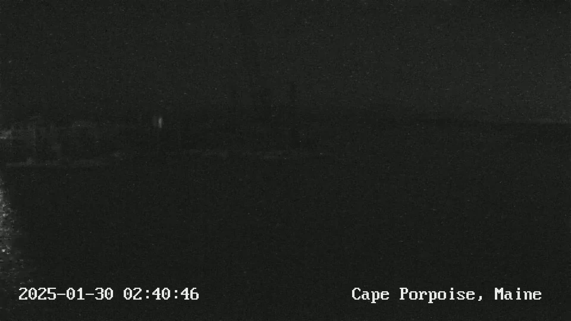 A very dark, nighttime image shows a mostly featureless, dark landscape.