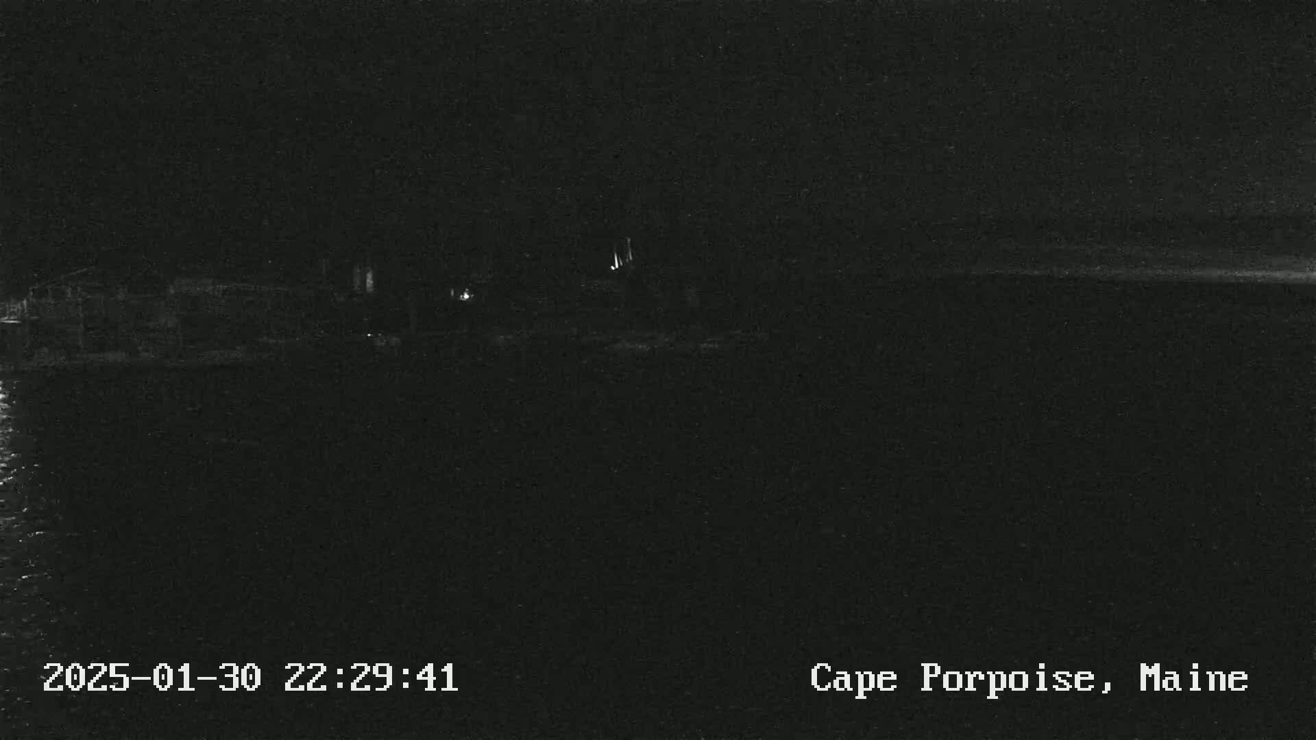 A nighttime, low-light view of a dark shoreline and body of water.