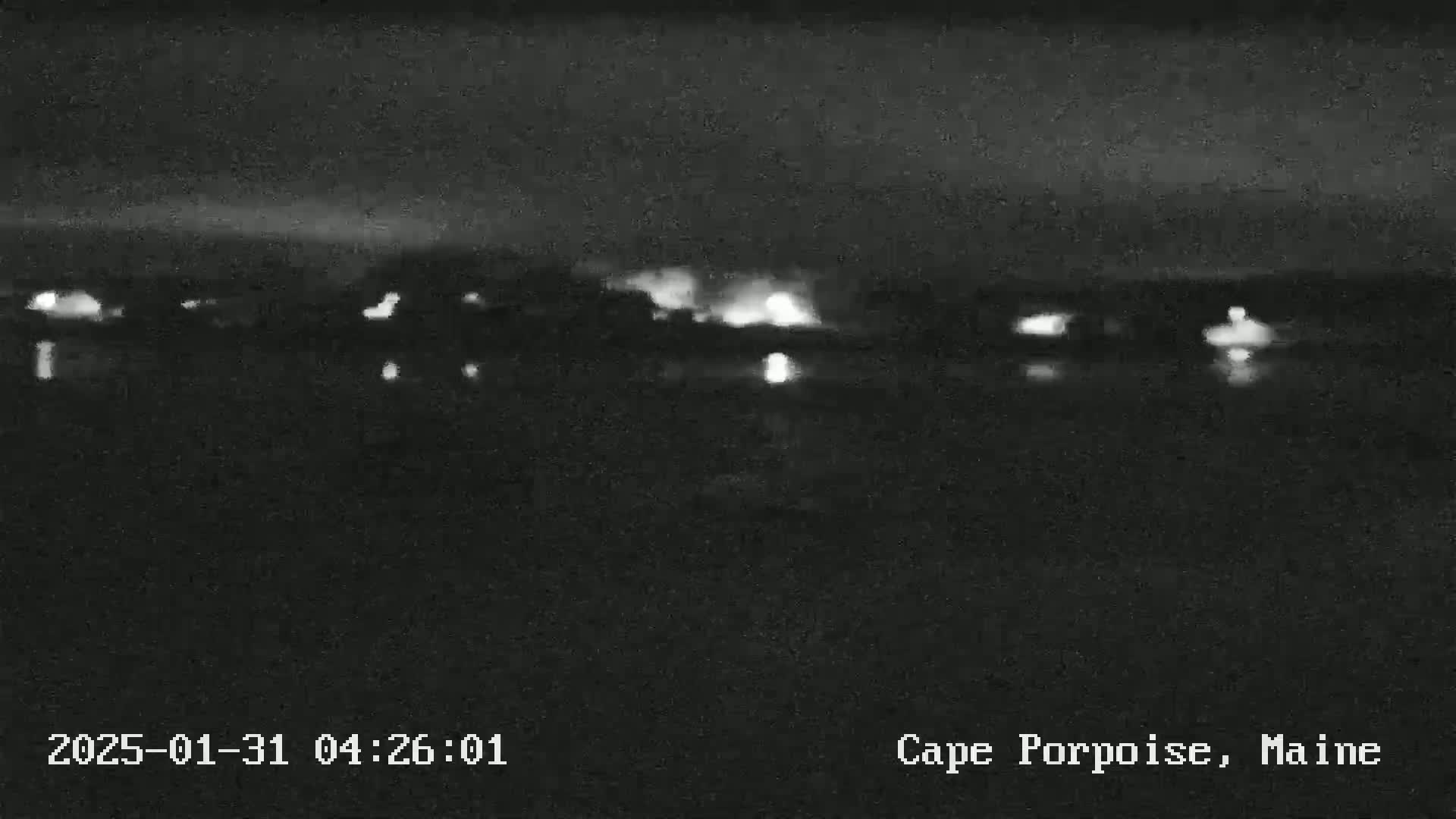 A nighttime, low-light view of a body of water with faintly visible lights on the far shore.