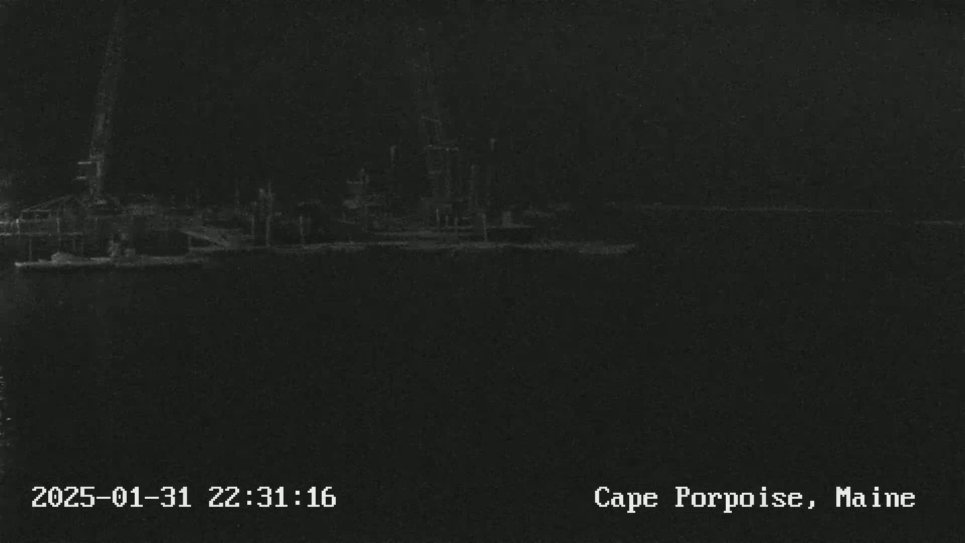 A nighttime, low-light image shows an industrial waterfront scene.