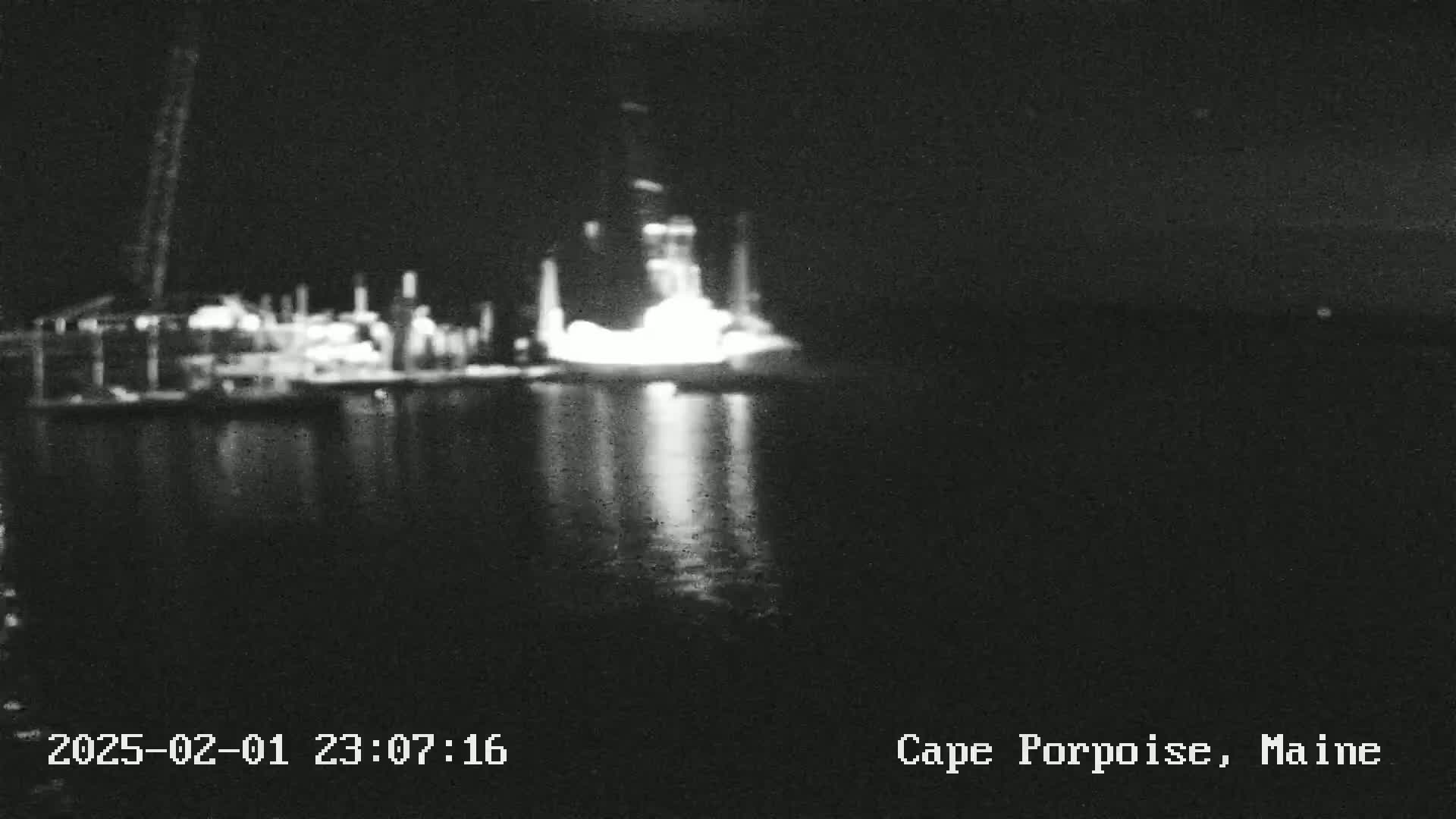 A blurry, nighttime image shows brightly lit structures on a dark body of water.
