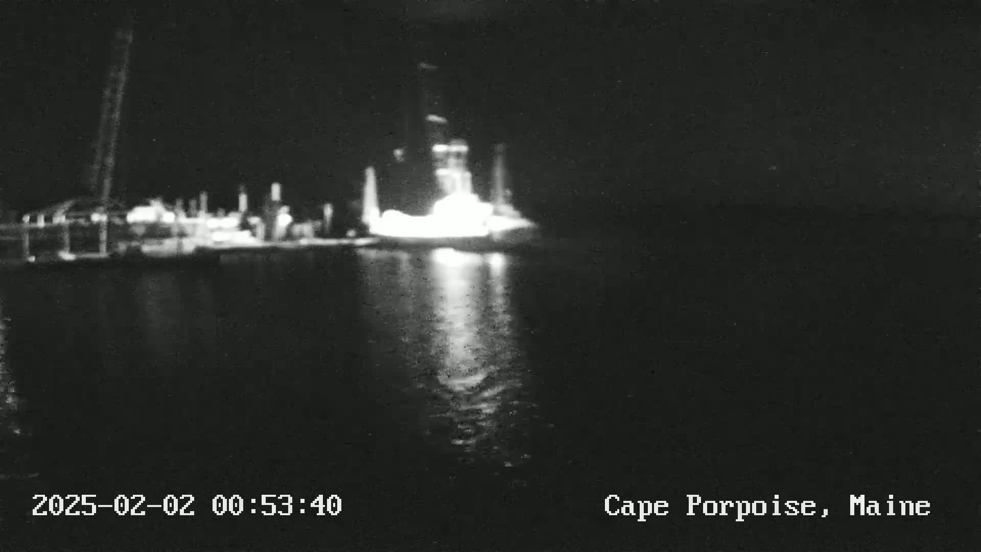 A brightly lit structure is visible on the water at night, reflecting light onto the dark water.