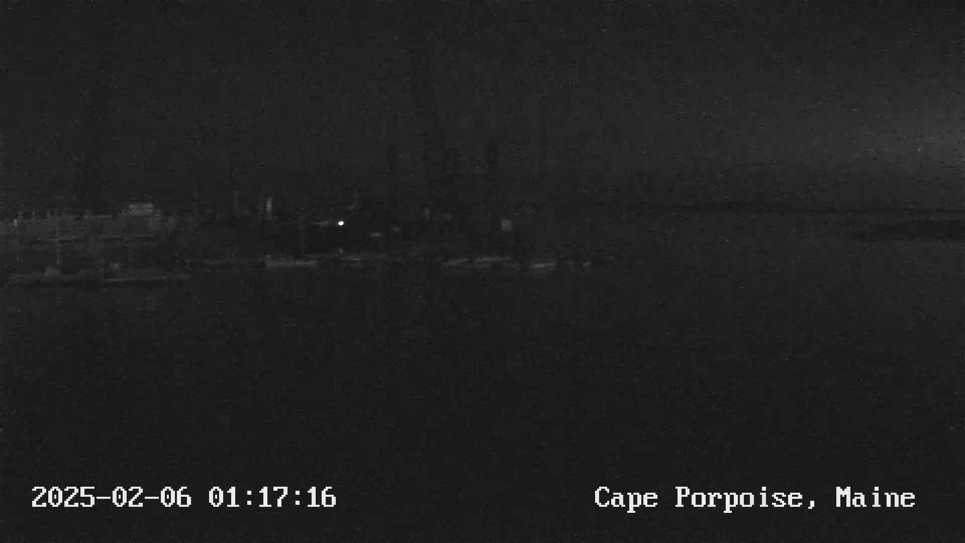 A nighttime, low-light view shows a dark, mostly featureless landscape with a few indistinct structures in the distance.