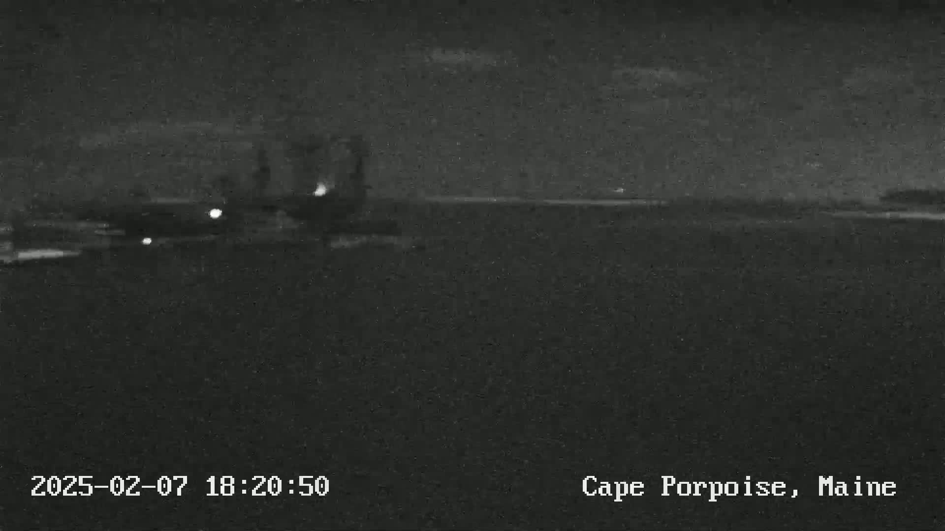 A nighttime, low-light image shows a dark body of water under a mostly clear sky.